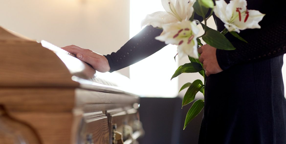 woman with lily flowers and coffin at funeral
